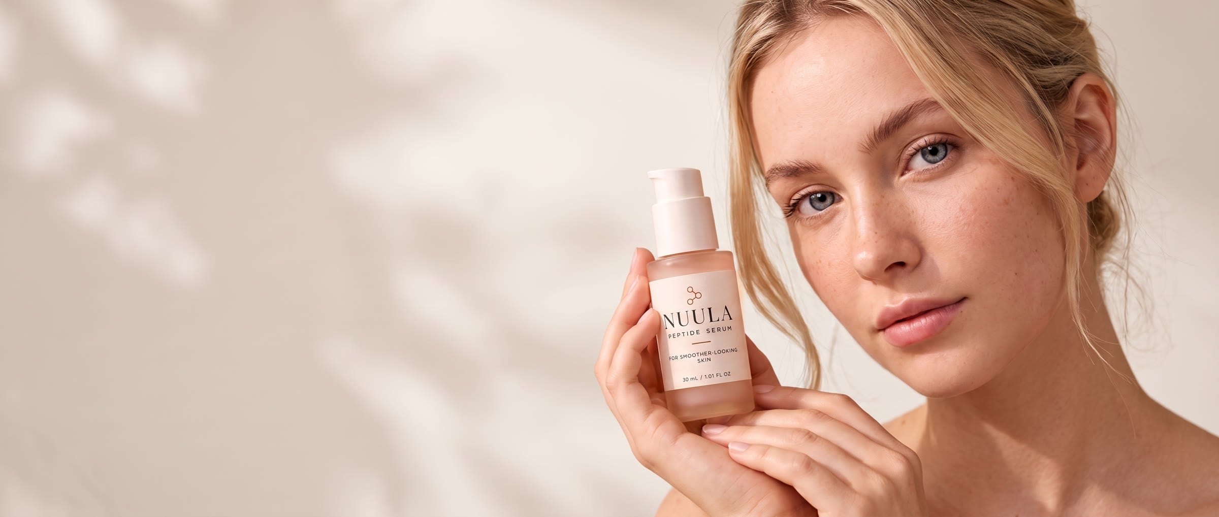 Woman holding the NUULA Peptide Serum under her chin